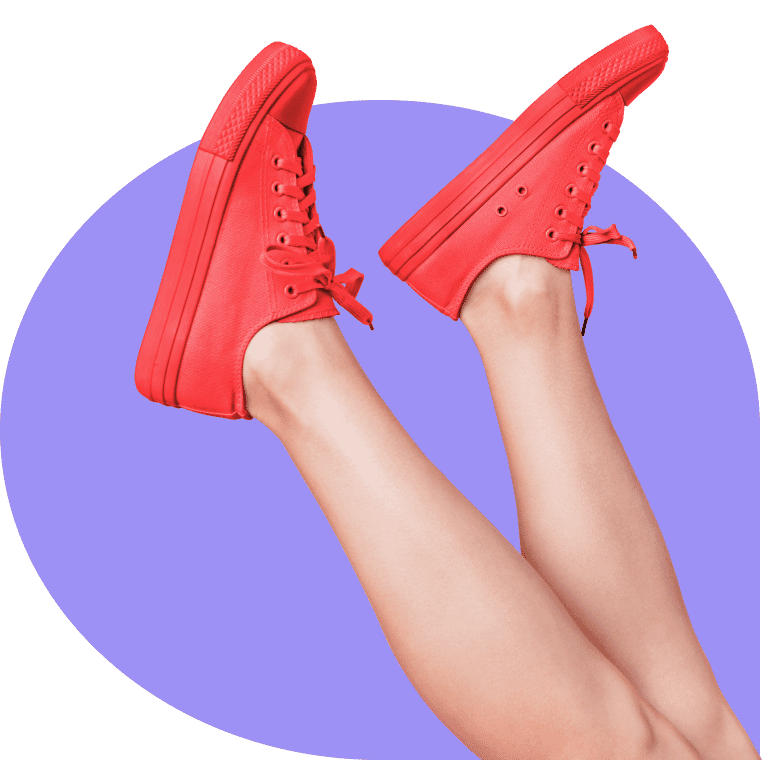 Red sneakers worn on crossed legs against a purple background, highlighting clipping path editing for a clean and vibrant finish.